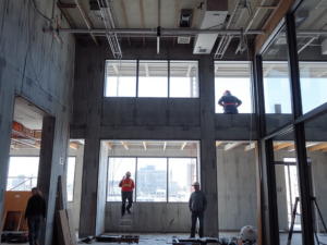 Công nhân đang thi công lắp đặt vách thạch cao ngăn phòng trong không gian nội thất hiện đại, ánh sáng tự nhiên chiếu vào tạo nên không gian làm việc chuyên nghiệp và sáng sủa